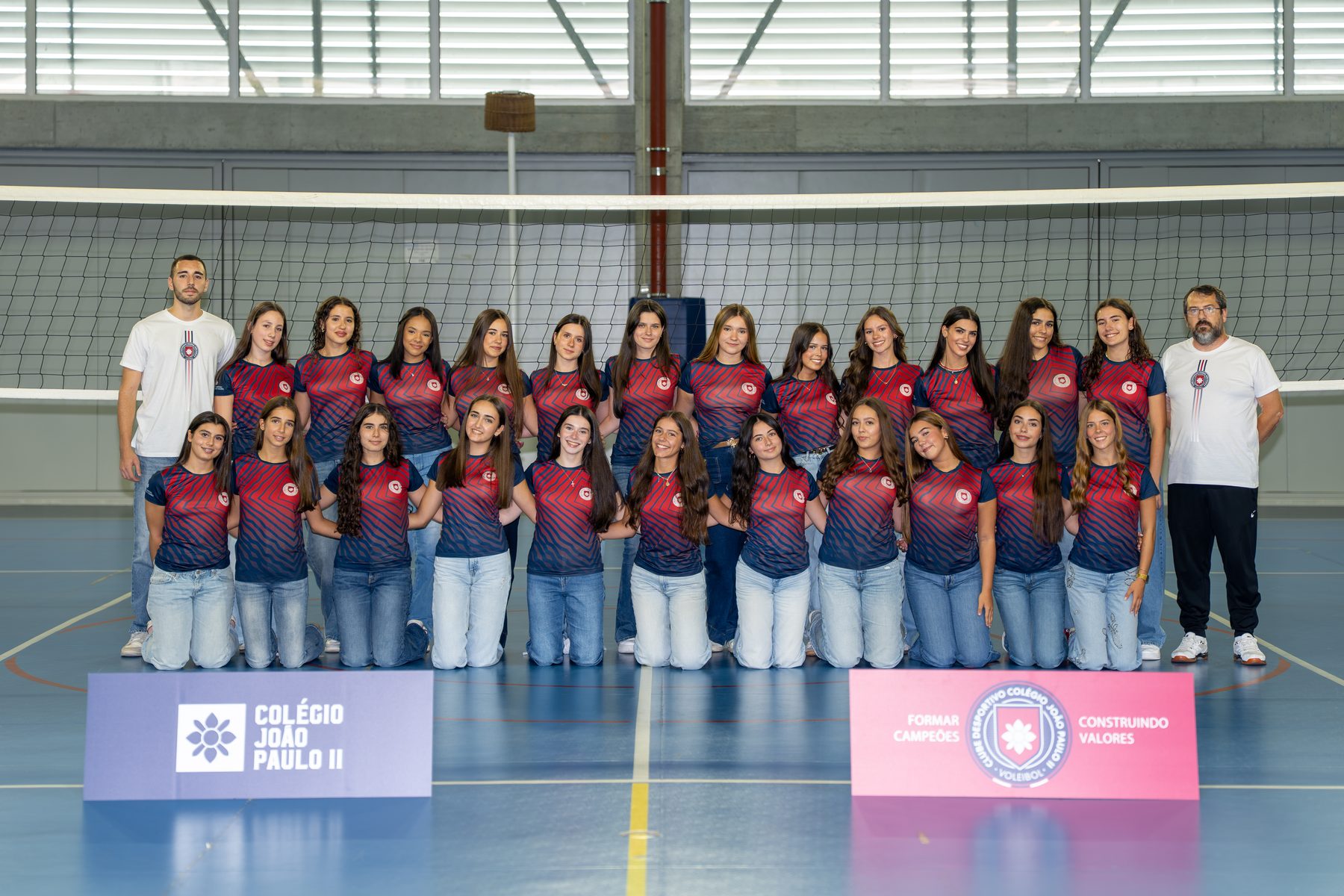 Equipa de voleibol feminino do Clube Desportivo do Colégio João Paulo II, com os dois treinadores, junto à rede